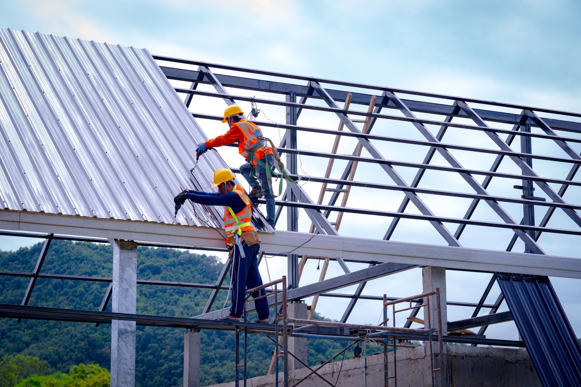Construction workers securing metal panels during a commercial roofing installation on a warehouse.