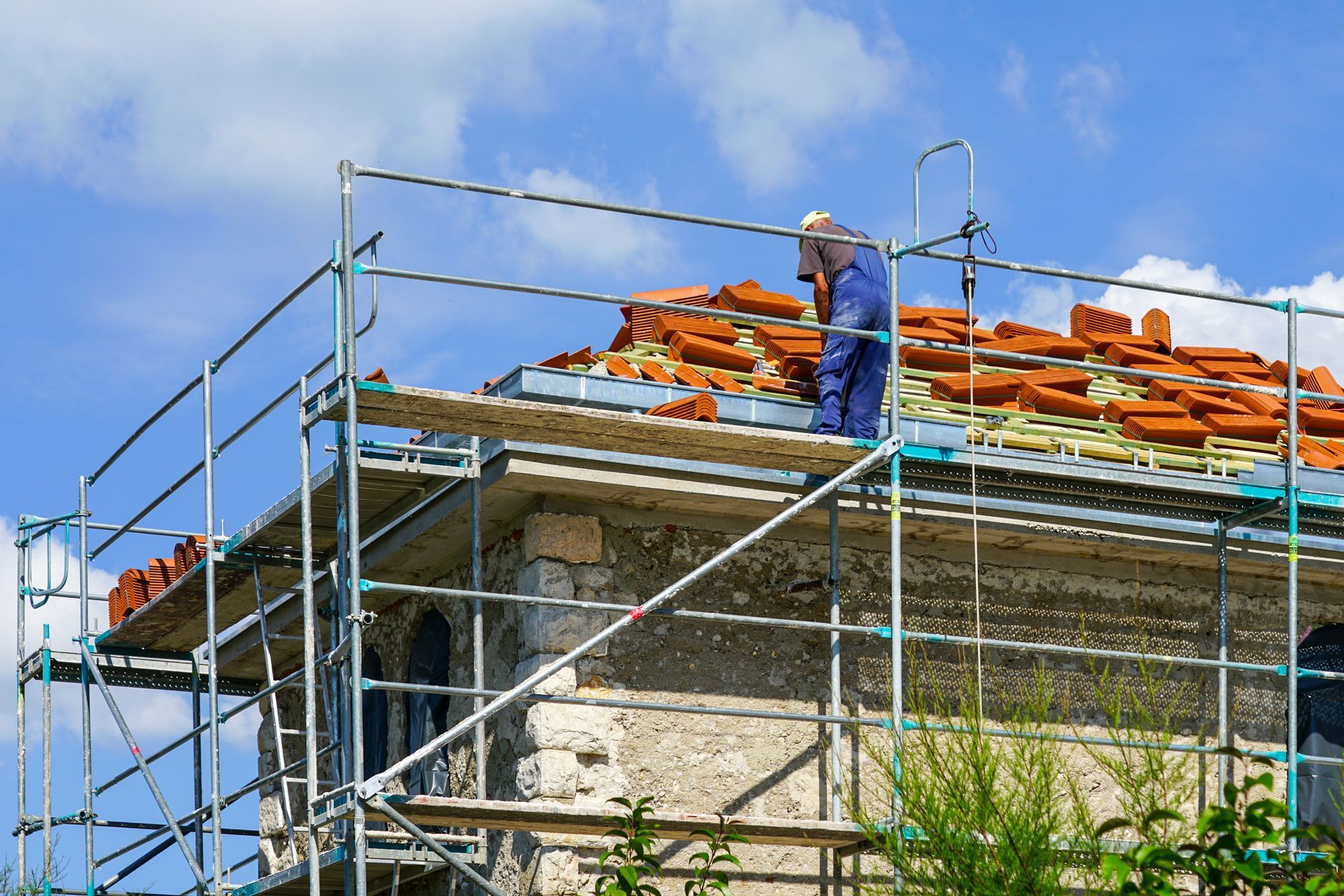 A man is replacing a clay tile roof.