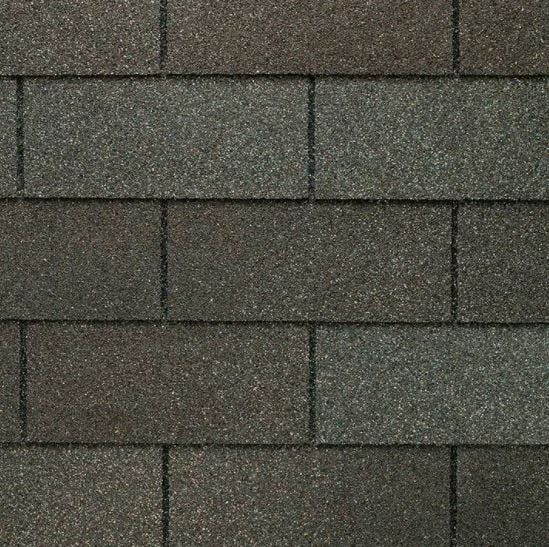 Close-up of asphalt roof shingles in shades of brown, gray, and green.