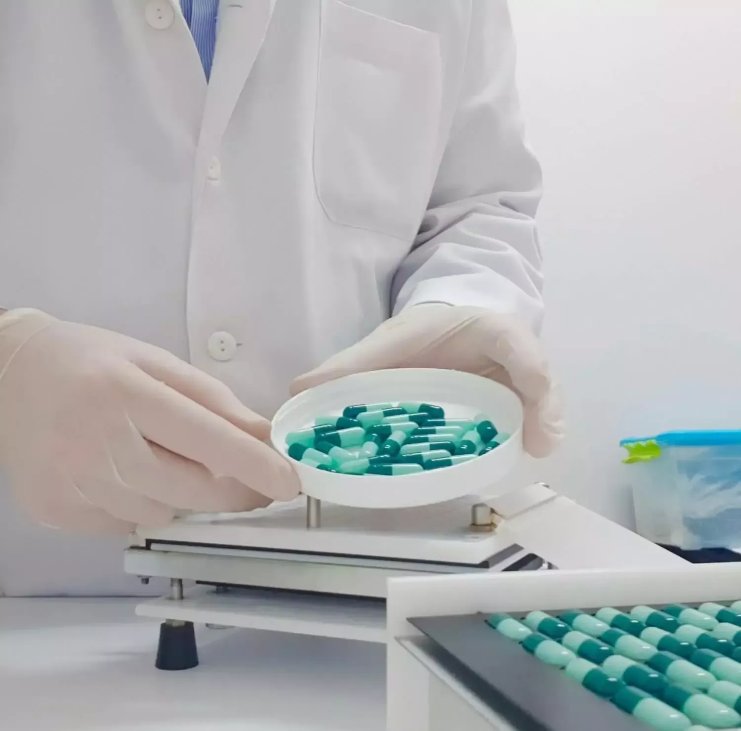 A doctor is holding a bowl of green capsules.