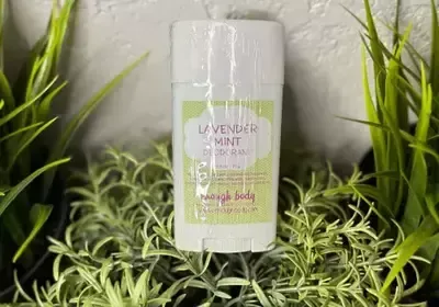 A bottle of lavender mint deodorant is sitting on top of a plant.