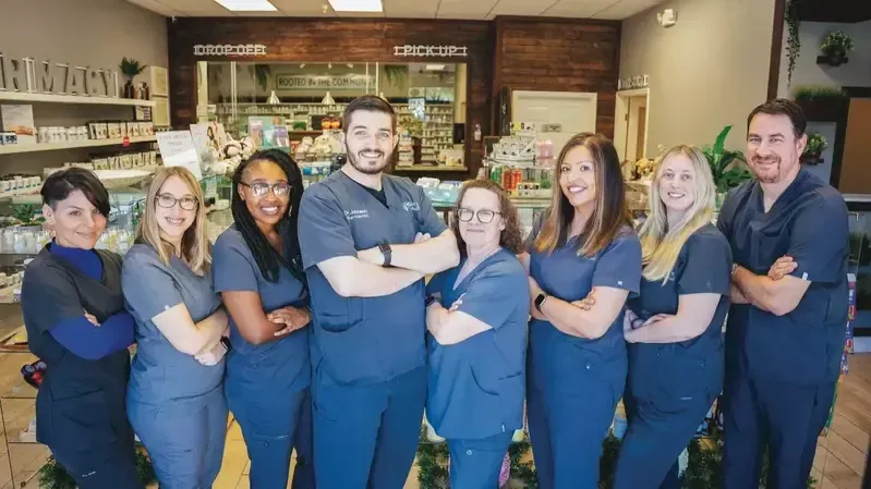 A group of people in scrubs are posing for a picture in a pharmacy.