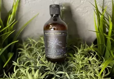 A bottle of body wash is sitting on top of a plant.