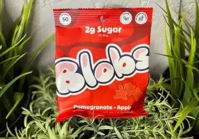 A bag of blobs candy is sitting on top of a lush green plant.
