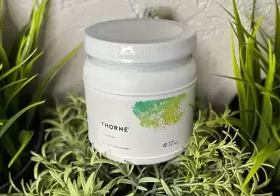 A white jar is sitting on top of a pile of green plants.