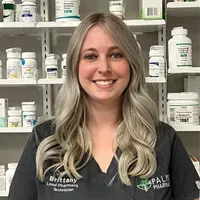 A woman is standing in front of a pharmacy shelf filled with bottles of medication.