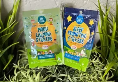Two bags of mood calming stickers and sleep promoting stickers are sitting on top of a plant.
