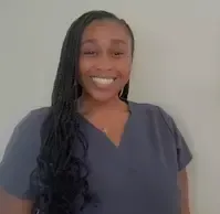 A woman in a scrub top is smiling for the camera.