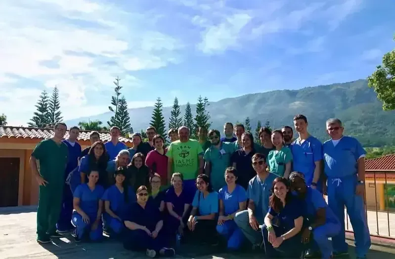 A group of people posing for a picture with mountains in the background.