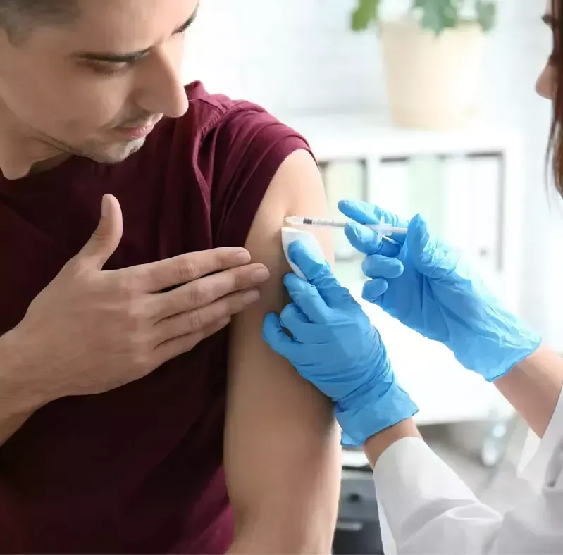A man is getting an injection in his arm by a doctor