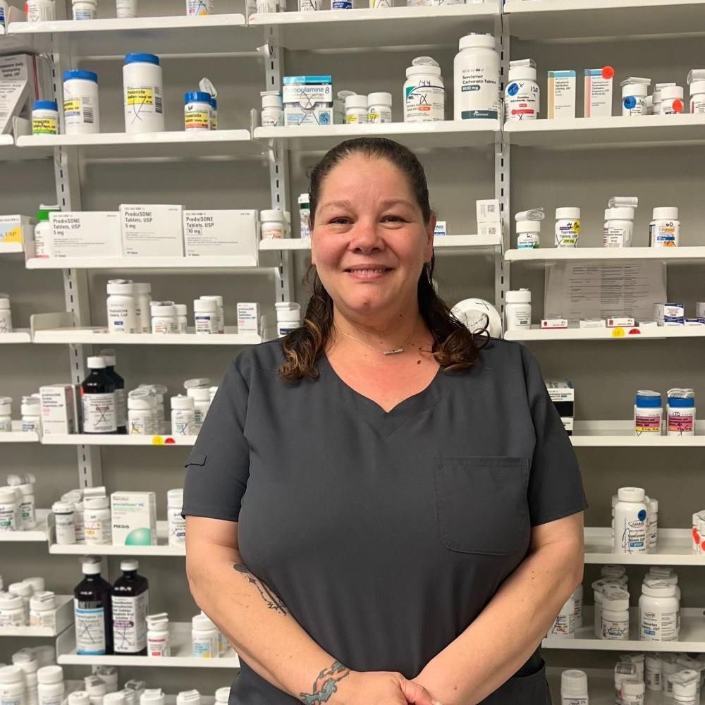 A woman in a palms pharmacy uniform is smiling