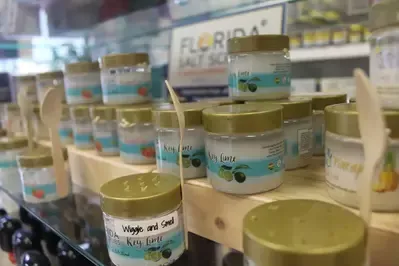 There are many jars of cream on a shelf in a store.