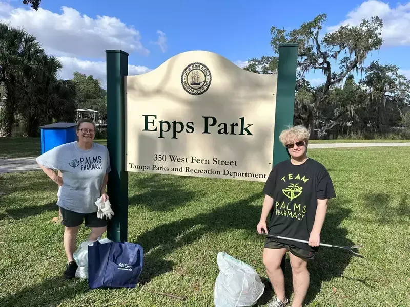 Two people are standing in front of a sign for epps park.