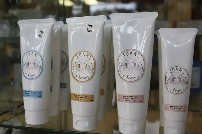 Four tubes of soap are lined up on a glass shelf.