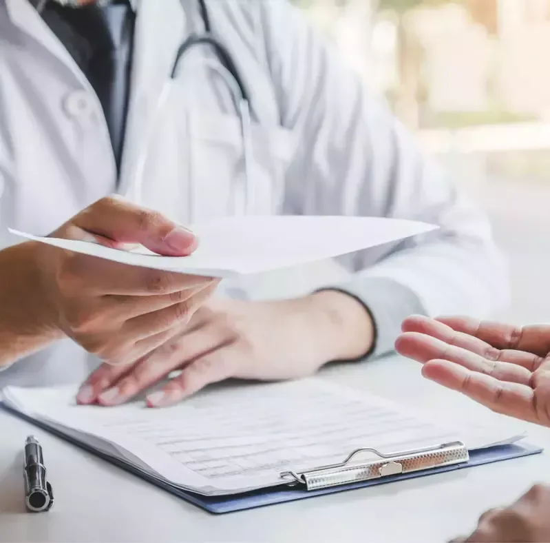 A doctor is giving a patient a piece of paper.