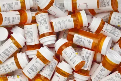 A pile of empty prescription bottles are stacked on top of each other.