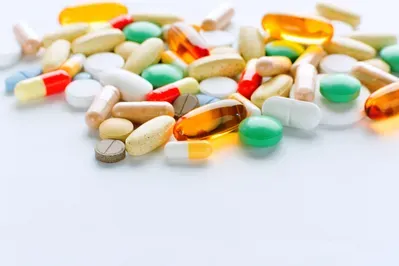 A pile of colorful pills and capsules on a white surface.