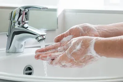 A person is washing their hands in a bathroom sink.