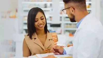 A pharmacist is talking to a woman in a pharmacy.