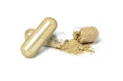 A capsule with powder coming out of it on a white background.