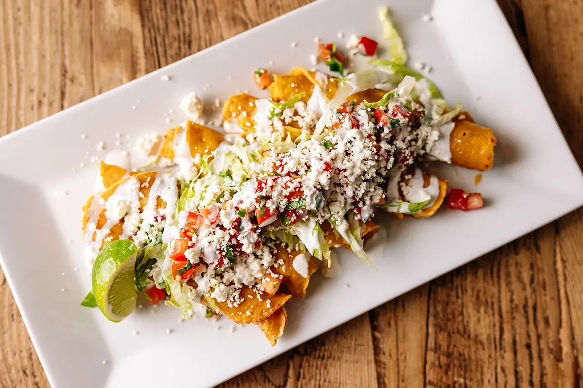 A white plate topped with a variety of mexican food on a wooden table.
