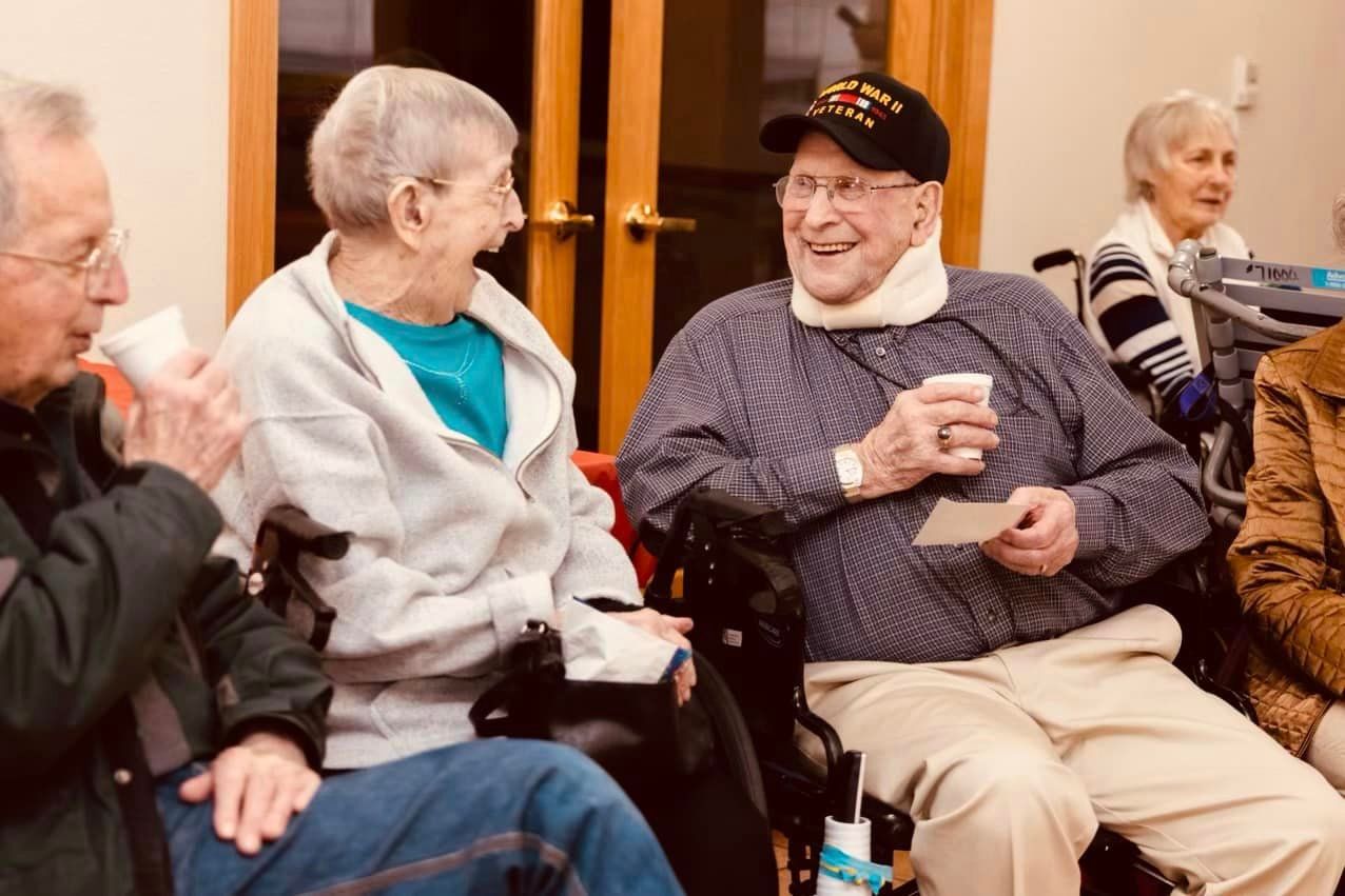 A group of elderly people are sitting in a circle talking to each other.