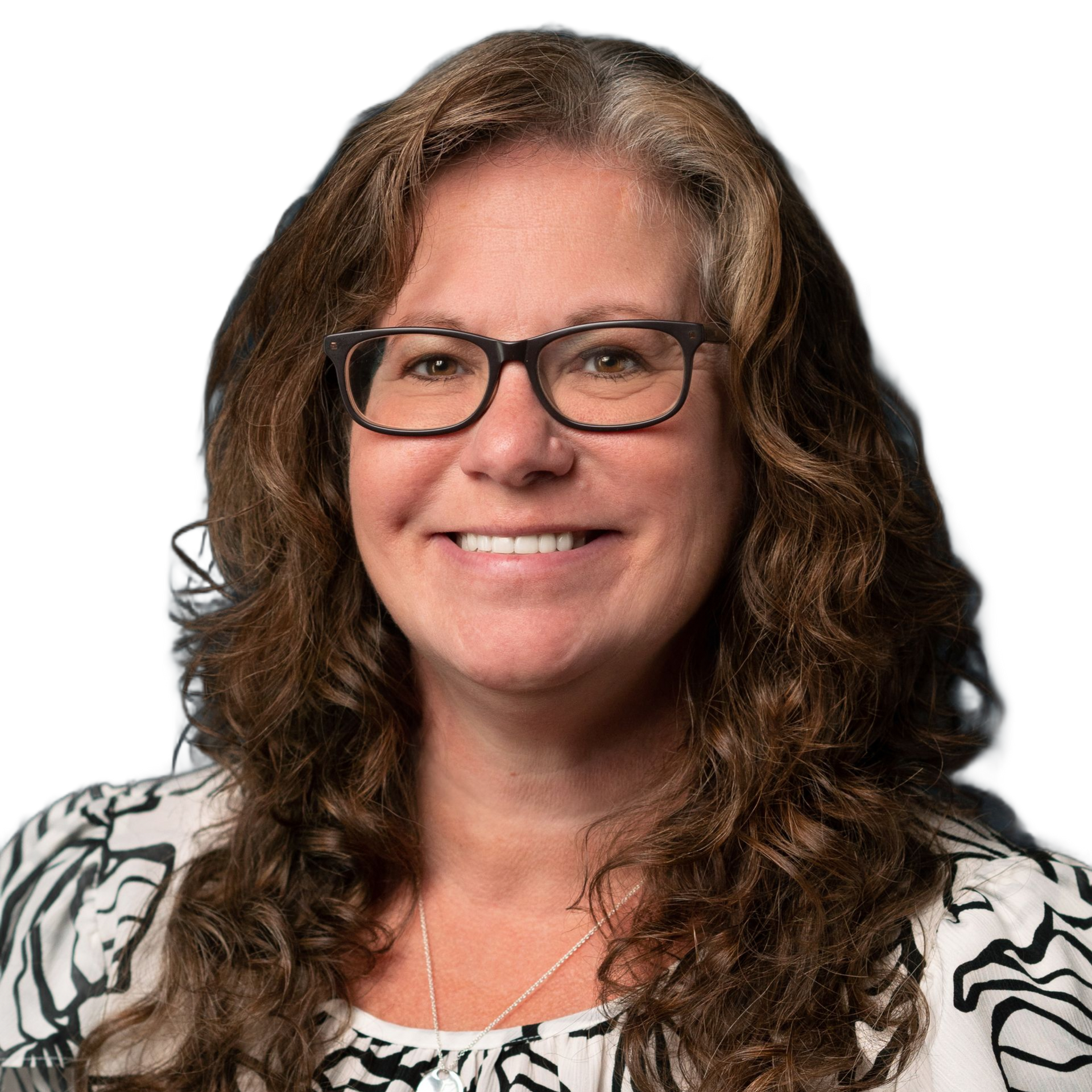 Woman with glasses smiles, wearing a patterned top, in front of a white background.