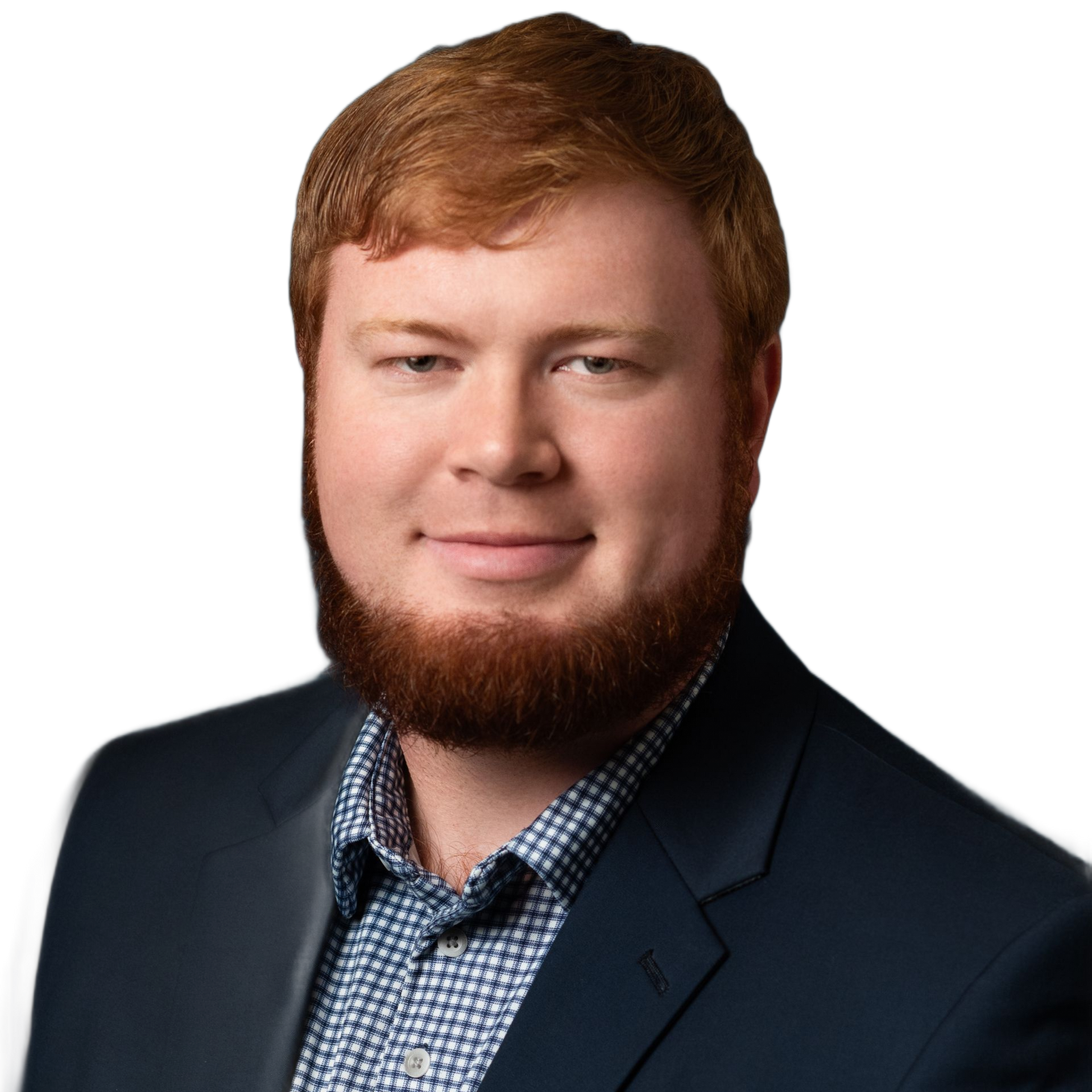 Man with red hair and beard, wearing a navy blazer and patterned blue shirt, smiling.