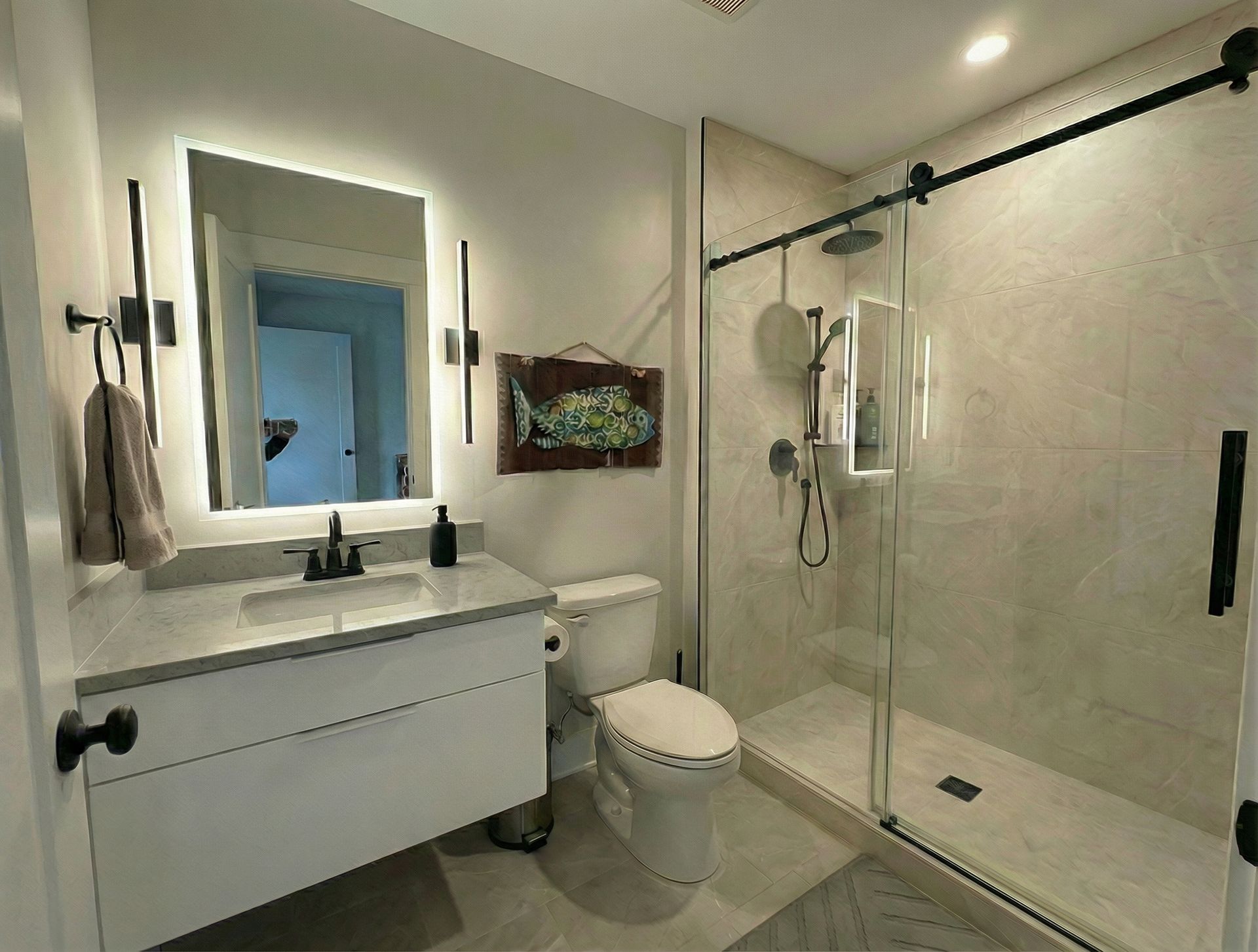 Modern white bathroom with vanity, toilet, and glass walk-in shower