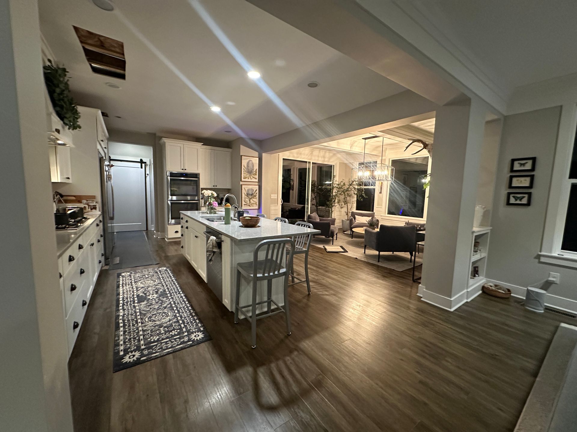 Open kitchen and living area with island, hardwood floors, and recessed lighting