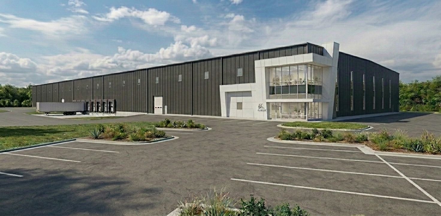 Modern black industrial building with large windows beside an empty parking lot