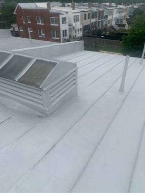 White flat roof with skylight vent, overlooking nearby brick and white apartment buildings