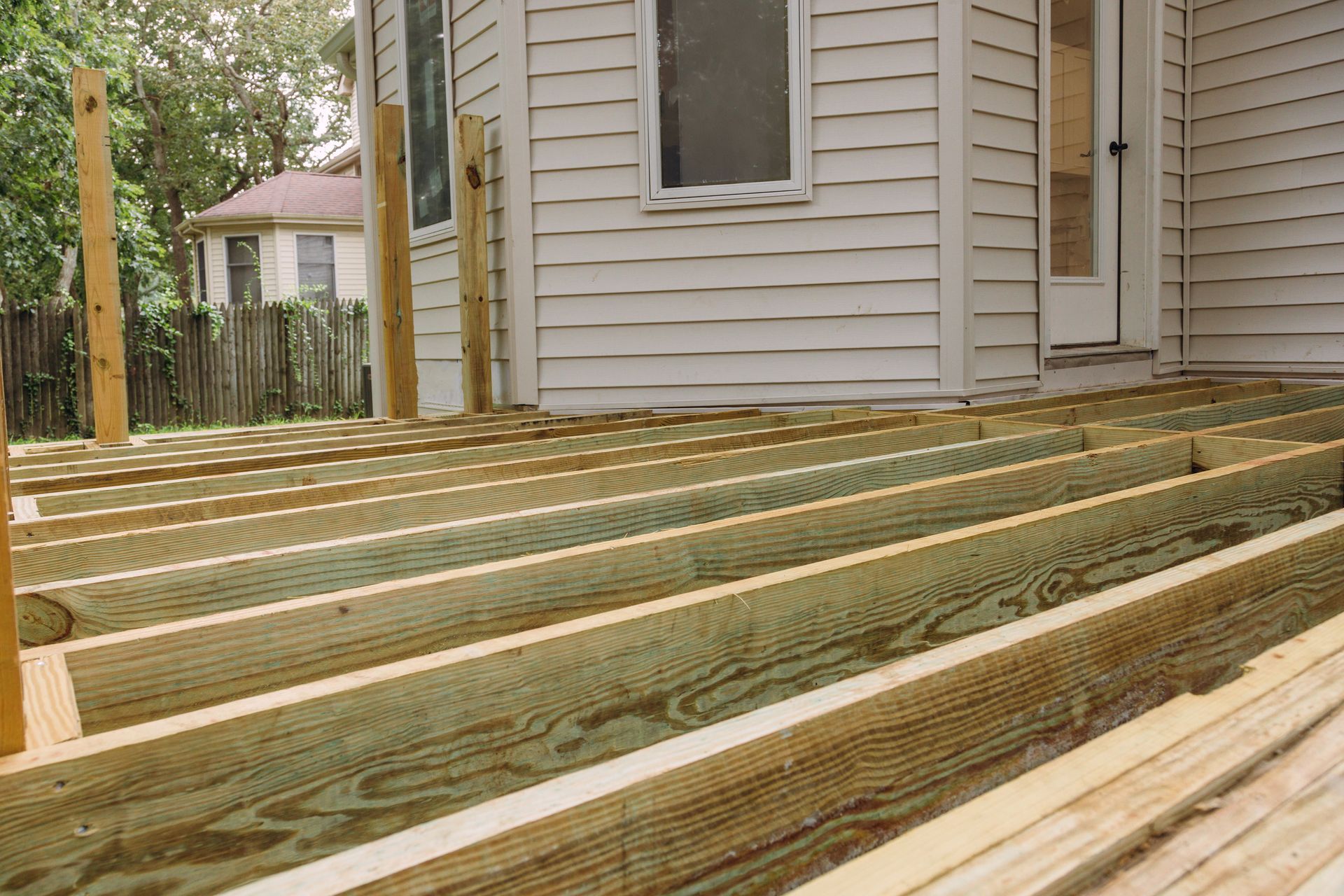New wooden deck framing beside a house and fence