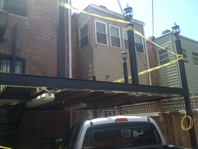 Brick apartment building with a metal canopy and a white pickup truck parked below
