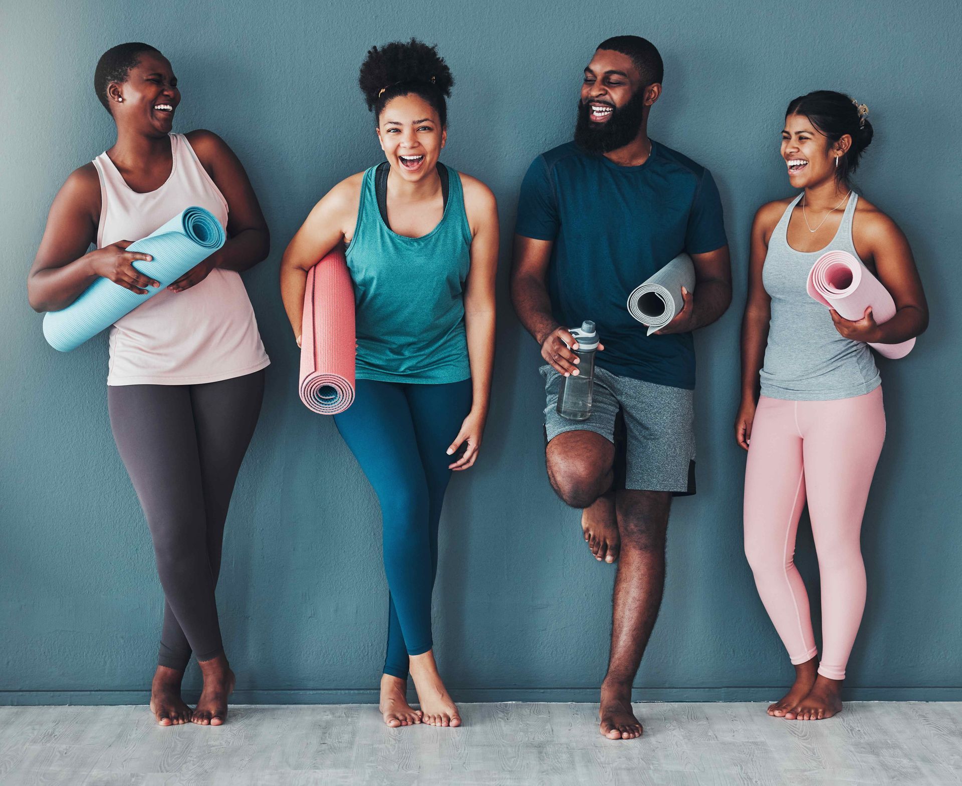 a group of people are standing next to each other holding yoga mats 