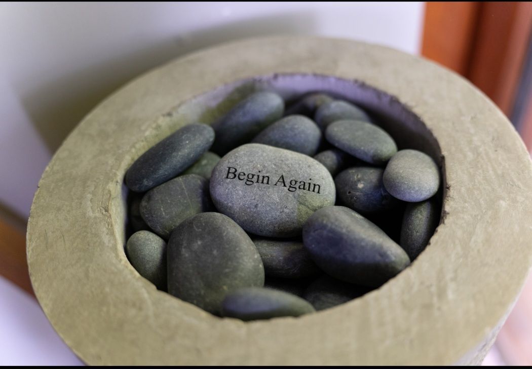 A pile of rocks with one that says begin again