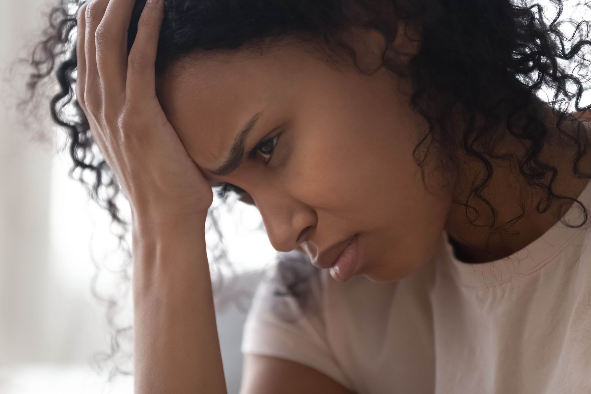 a woman is sitting on a couch with her head in her hands