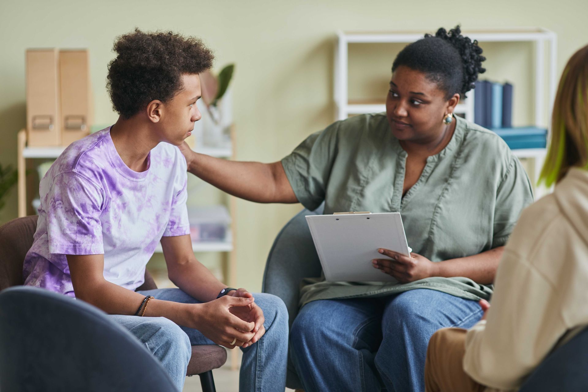 a woman is comforting a young boy during a group therapy session