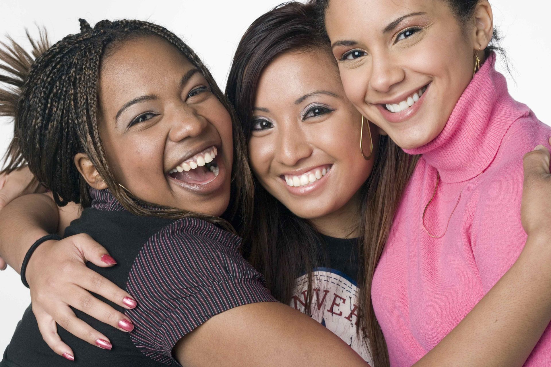 three women hugging each other with one wearing a pink turtleneck
