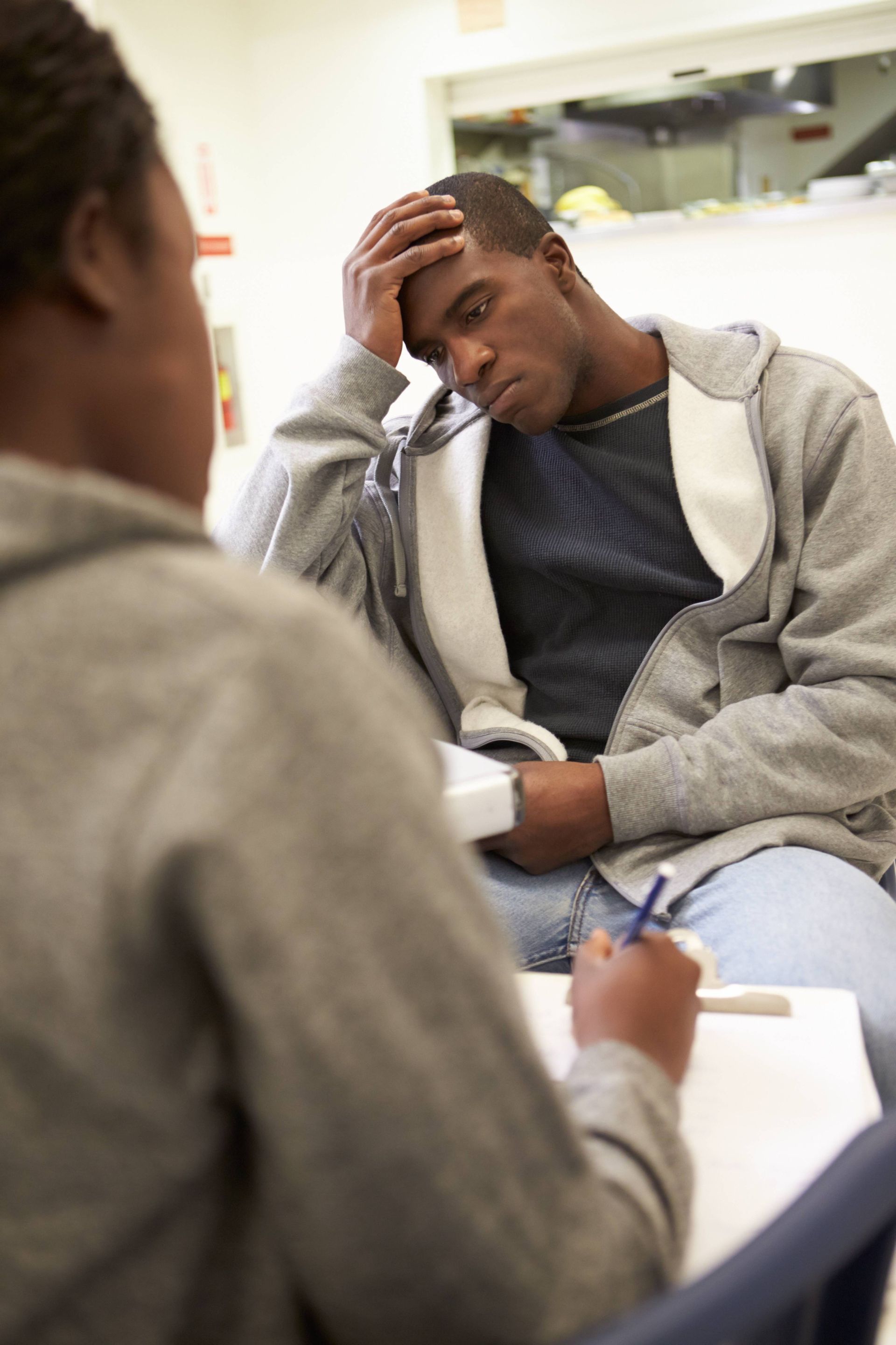 a man is sitting at a table talking to a woman who is writing on a piece of paper
