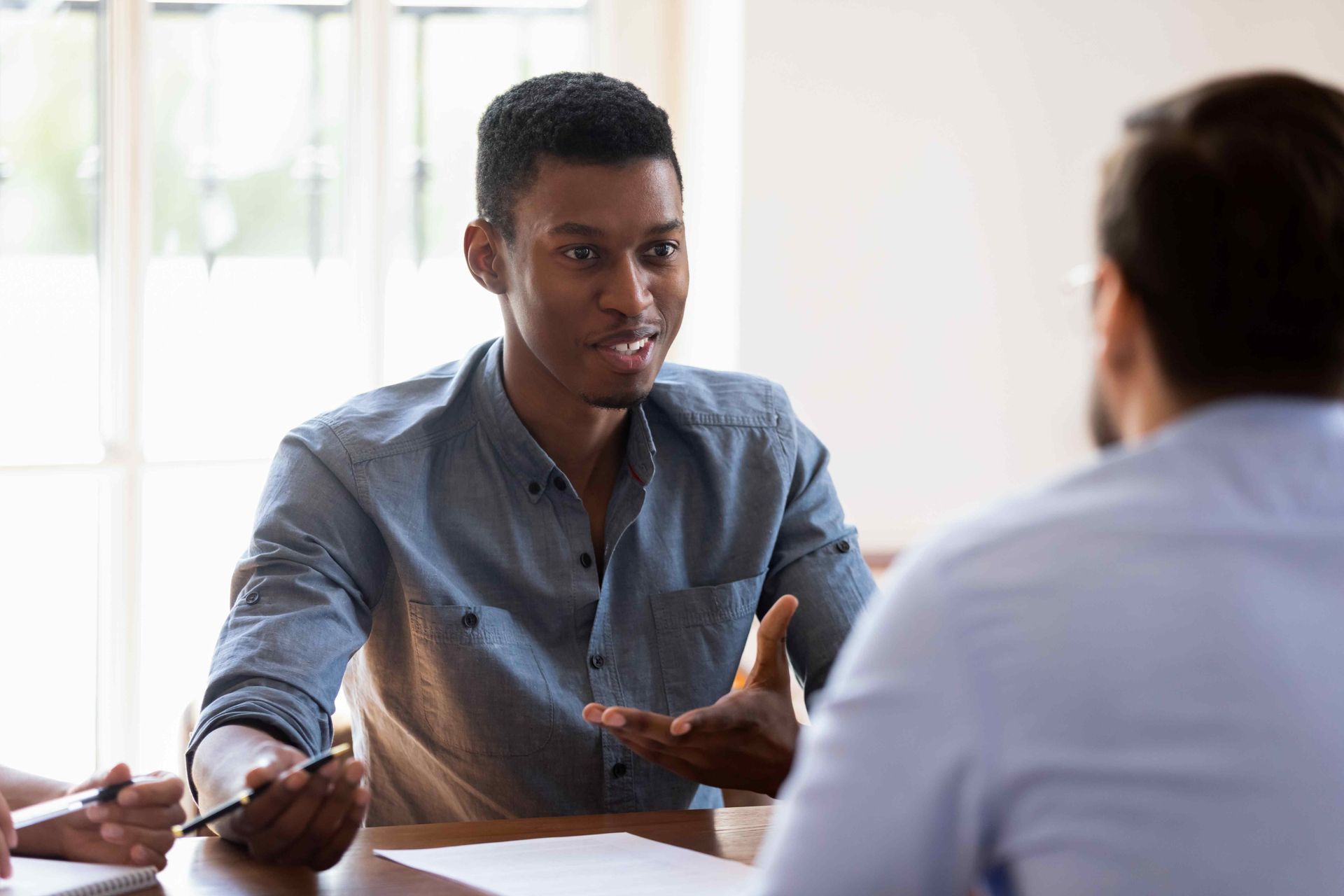 a man is sitting at a table talking to another man