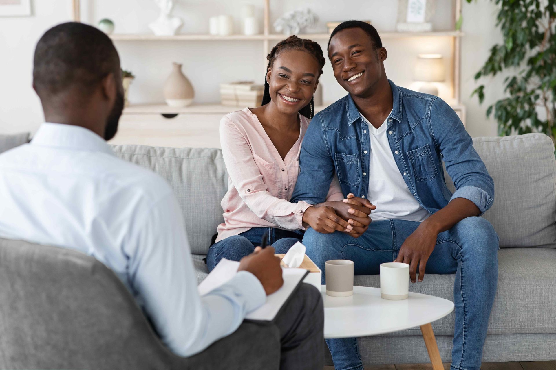 a man and woman are sitting on a couch talking to a counselor
