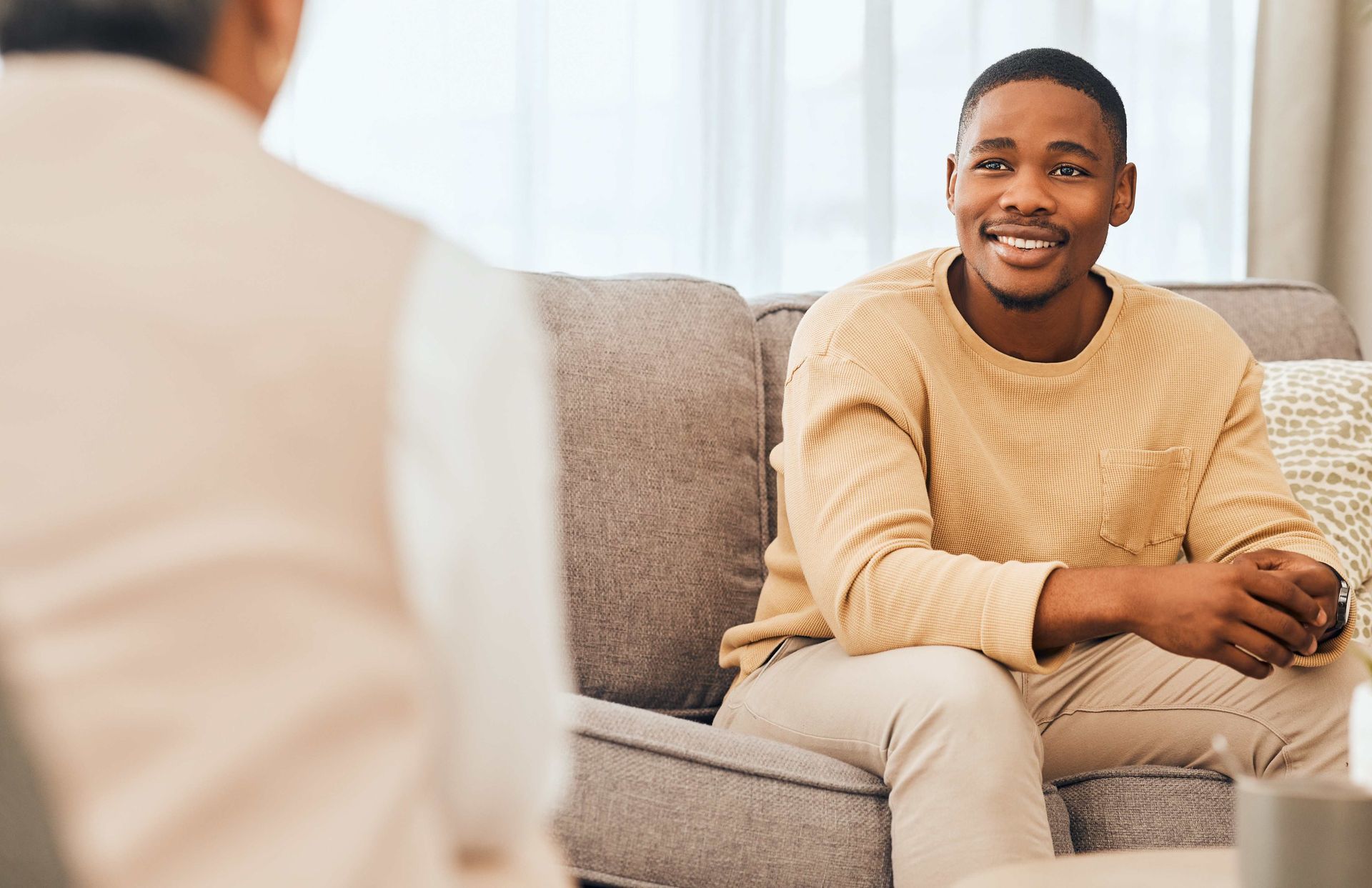 a man is sitting on a couch talking to another man