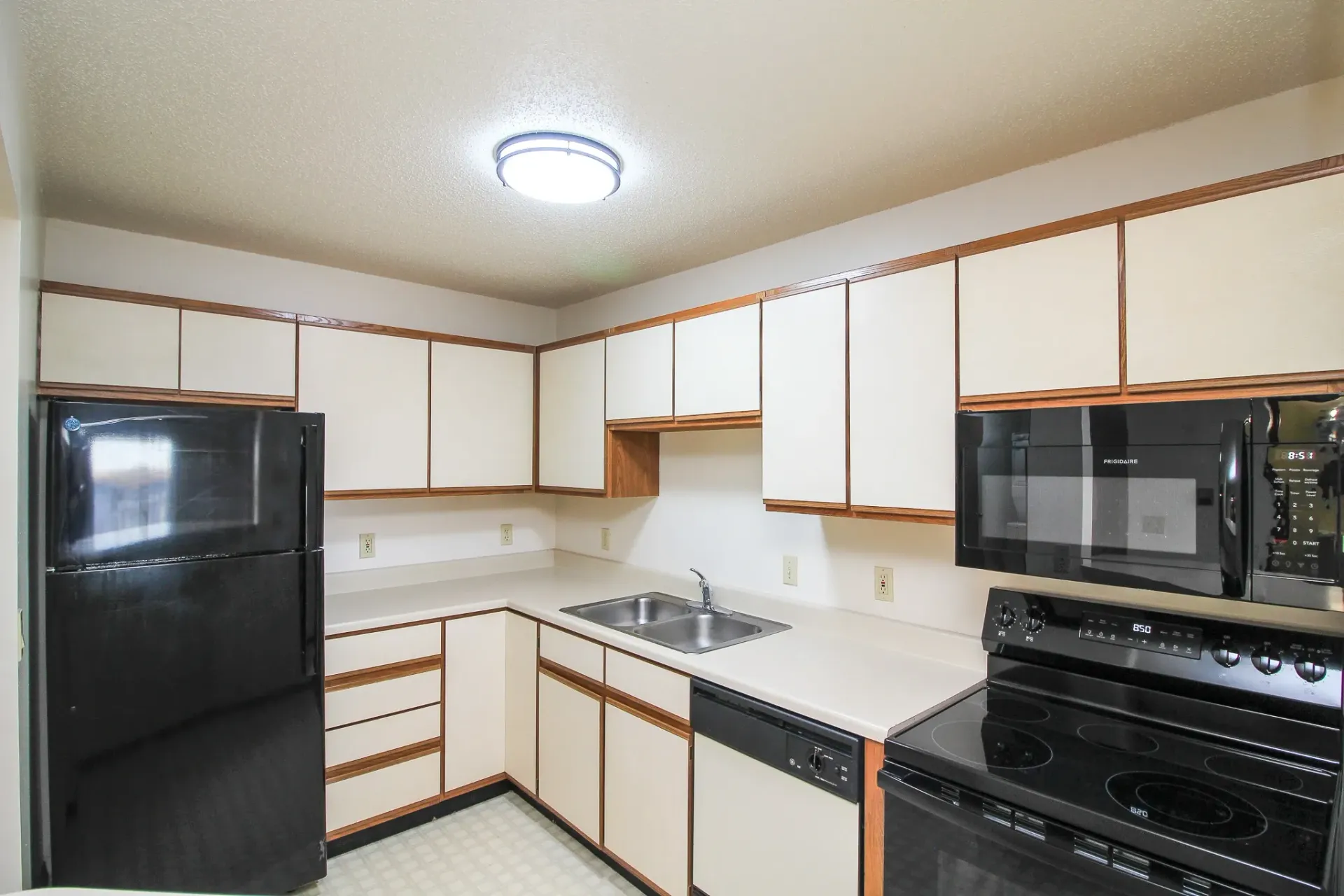 Bright kitchen with white cabinets, black appliances, and a tiled floor
