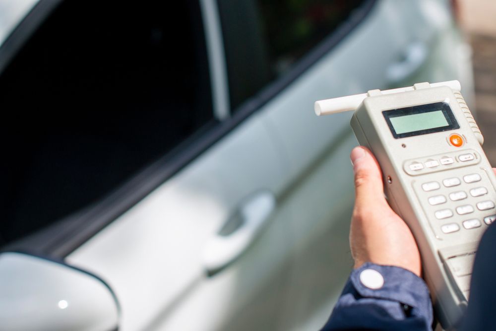 A Person Is Holding a Breathalyzer in Front of A Car — A & K Auto Electrical & Air Conditioning in Quirindi, NSW