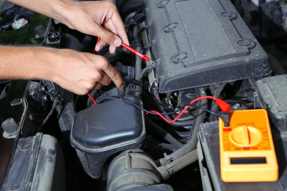 A Person Is Working On A Car Engine With A Multimeter — Auto Electrical & Air Conditioning in Quirindi, NSW
