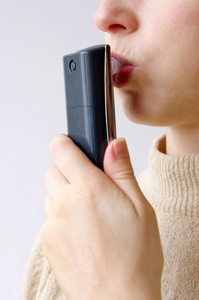 A Woman Is Holding a Breathalyzer to Her Mouth — A & K Auto Electrical & Air Conditioning in Tamworth, NSW