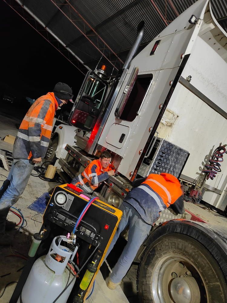 A Group of Men Are Working on a Semi Truck in a Garage — Auto Electrical & Air Conditioning in Tamworth, NSW