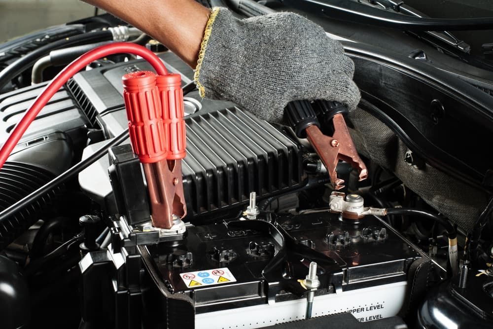 Technician connecting a jumper cable to a car battery — Auto Electrical & Air Conditioning in Tamworth, NSW