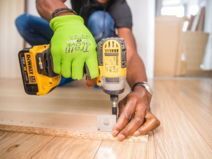 A person is using a drill on a piece of wood.